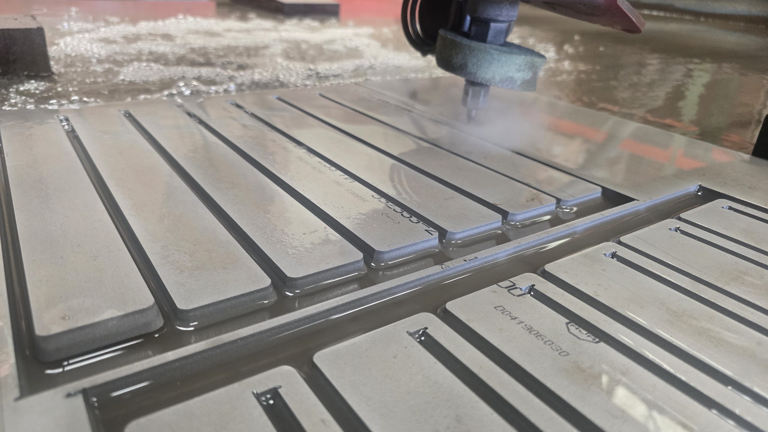 Waterjet head cutting a steel plate on the bed